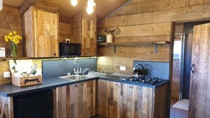 A rustic kitchen with wooden cabinets, a black microwave, and a sink. - Luxury Safari Lodge-Sleeps 4/6-Deer Park-Dogs Ok (Crediton)