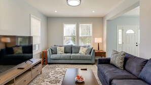 A living room with a grey sofa, a TV, a coffee table, and a lamp.