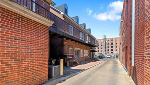 A narrow street lined with brick buildings, including a visible storefront with a sign that reads "atelier glass company."