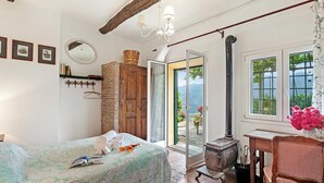 A bedroom with a bed, a wooden wardrobe, a window with a view, and a wooden table with a chair. - Ca Veggia for Nature Lovers with Views & Garden, Stellanello, Italy (Stellanello)