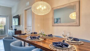 A dining area with a wooden table set for four, blue chairs, and a large mirror on the wall.