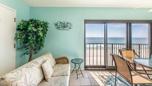 Une chambre avec vue sur l’océan, un balcon avec une table et des chaises, un canapé et une plante en pot.