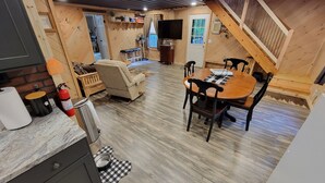 A cozy, well-lit basement with a wooden dining area, a fireplace, and a staircase leading upstairs.