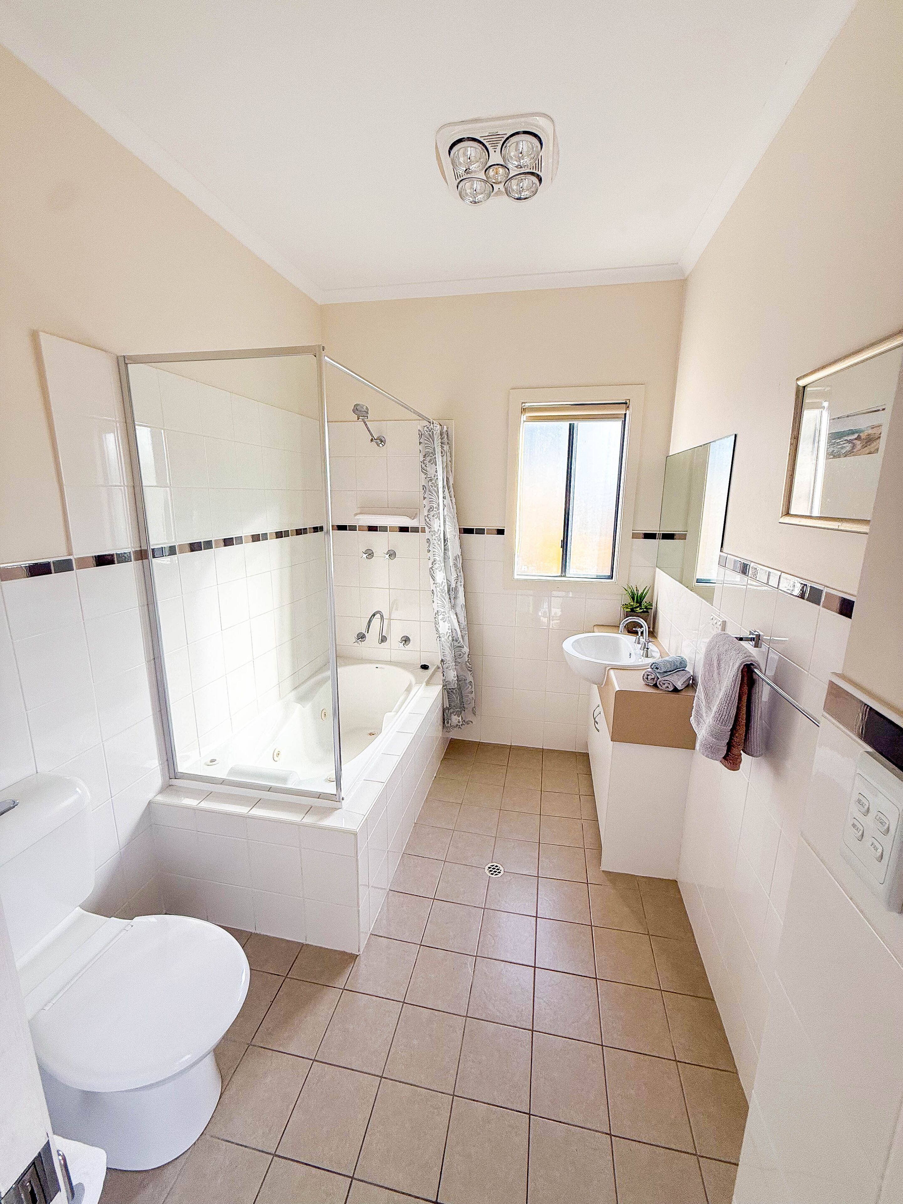 Ein modernes Badezimmer mit einer gläsernen Duschkabine, einer Badewanne, einer Toilette, einem Waschbecken und einem Fenster für natürliches Licht.