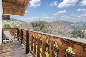 Une terrasse en bois offrant une vue sur un paysage montagneux.