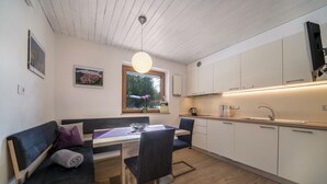 Eine moderne Küche mit weißen Schränken, einem Essbereich mit einer Bank und Stühlen sowie einem großen Fenster.