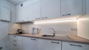 Eine moderne Küche mit weißen Schränken, einer Edelstahlspüle und einer integrierten Kaffeemaschine.