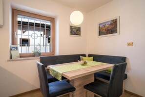 Un comedor con una mesa, sillas, un banco, una lámpara colgante y dos cuadros en la pared.
