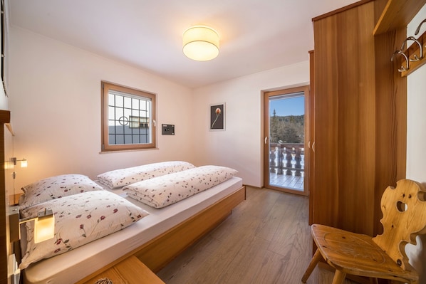 Un dormitorio con cama, mesitas de noche, una ventana y vistas al exterior.