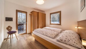 A bedroom with a bed, wooden wardrobe, and a chair. - Apartment "Hirzer" near Skiing Area with Forest View, Wi-Fi, Balcony & Shared Garden (Falzeben)