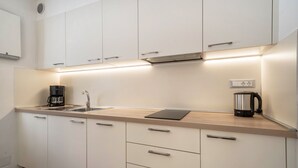 A modern kitchen with white cabinets, a wooden countertop, a coffee maker, and a kettle. - Apartment "Hirzer" near Skiing Area with Forest View, Wi-Fi, Balcony & Shared Garden (Falzeben)