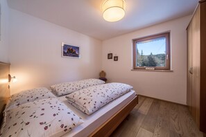 A bedroom with a bed, a nightstand, a window, and a wall-mounted picture.