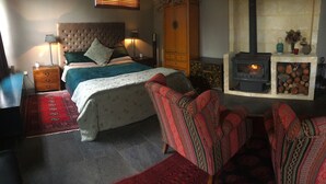 Une chambre à coucher avec un lit, une table de chevet, une lampe et une cheminée.