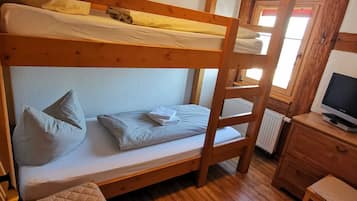 Ein Schlafraum mit Etagenbetten, einem Schreibtisch und Stuhl, Holzboden und einem Fenster mit Blick.