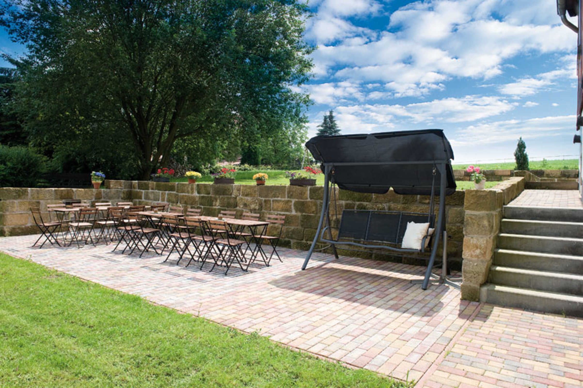 Eine Terrasse im Freien mit Backsteinboden, Grill und Tisch mit Stühlen.