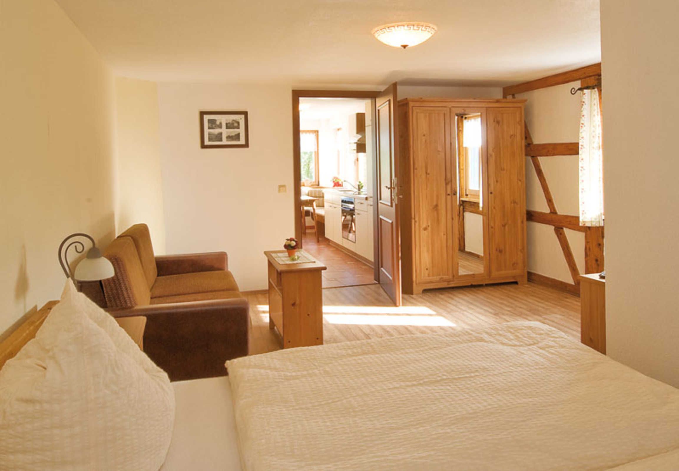Ein Schlafzimmer mit Bett, Sessel, Nachttisch und Holzschrank.