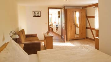 Ein Schlafzimmer mit Bett, Sessel, Nachttisch und Holzschrank.