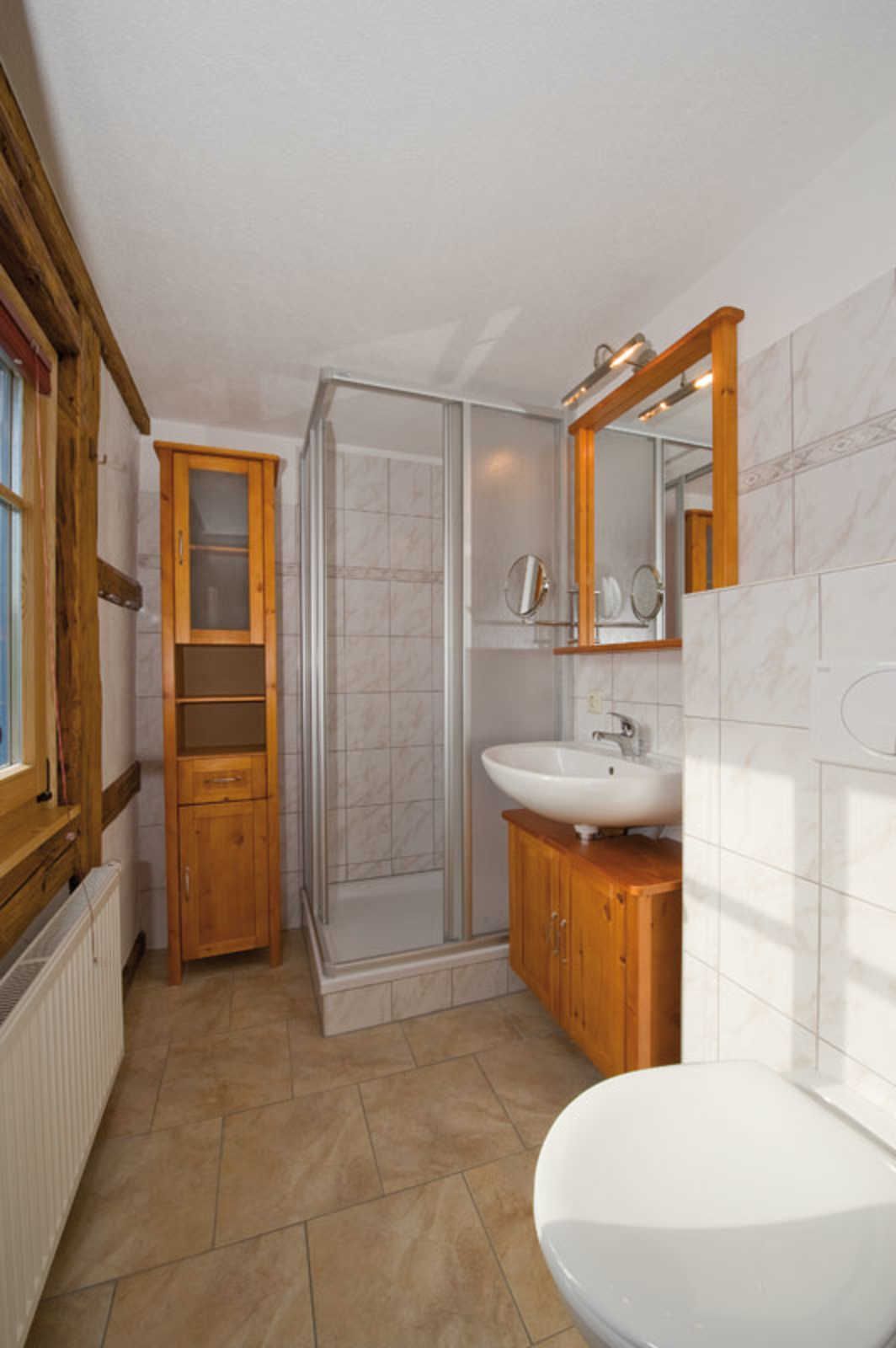 A bathroom with a white sink, wooden cabinets, and a glass shower enclosure.