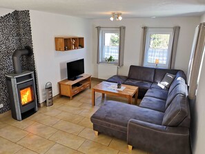 Uma sala de estar com lareira, sofá, televisão e prateleira de madeira.