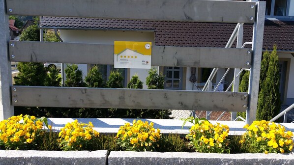 A metal gate with a yellow sign, surrounded by yellow flowers.