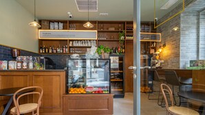 A cozy cafe with wooden furniture, a glass display case with fruits, and shelves stocked with beverages and snacks. - Lady Todd (Sliema)