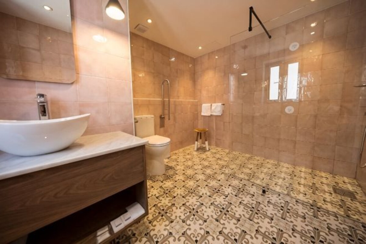 A bathroom with a large vessel sink, a toilet, and a shower area.