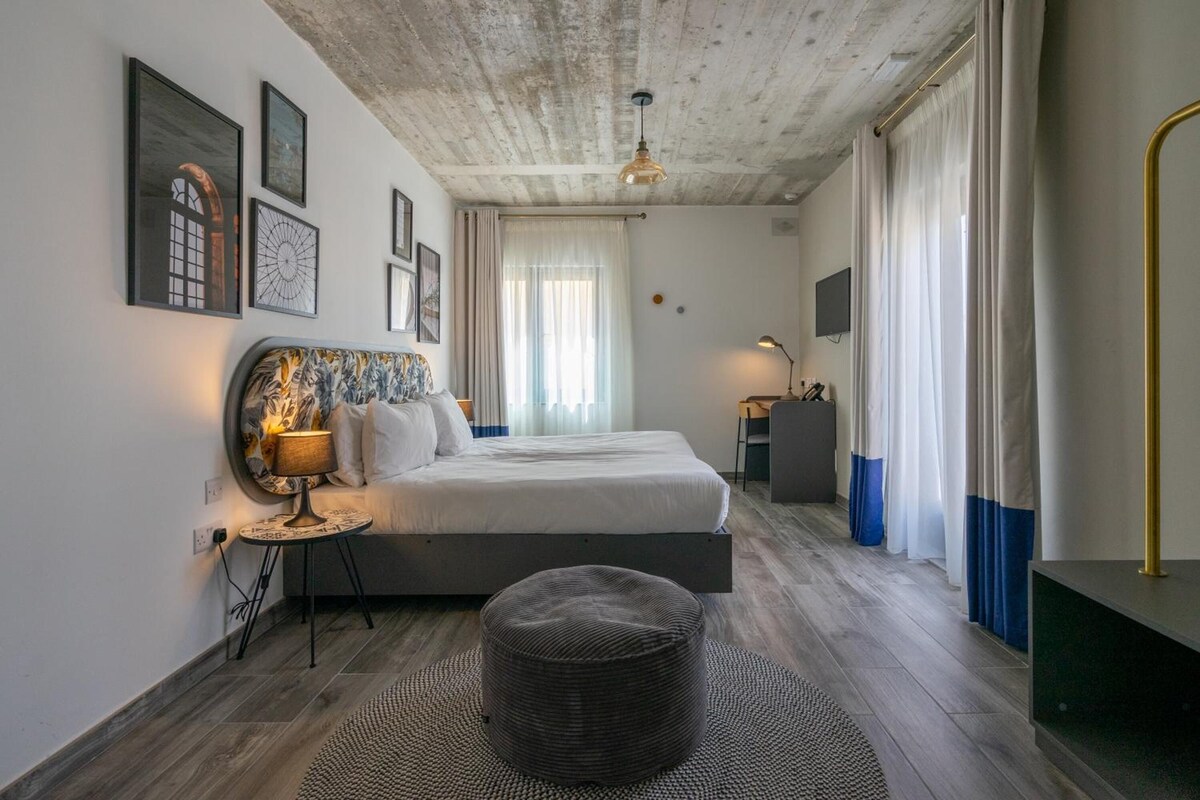 Une chambre à coucher moderne avec un lit, une table de chevet, une lampe et une œuvre d’art accrochée au mur.