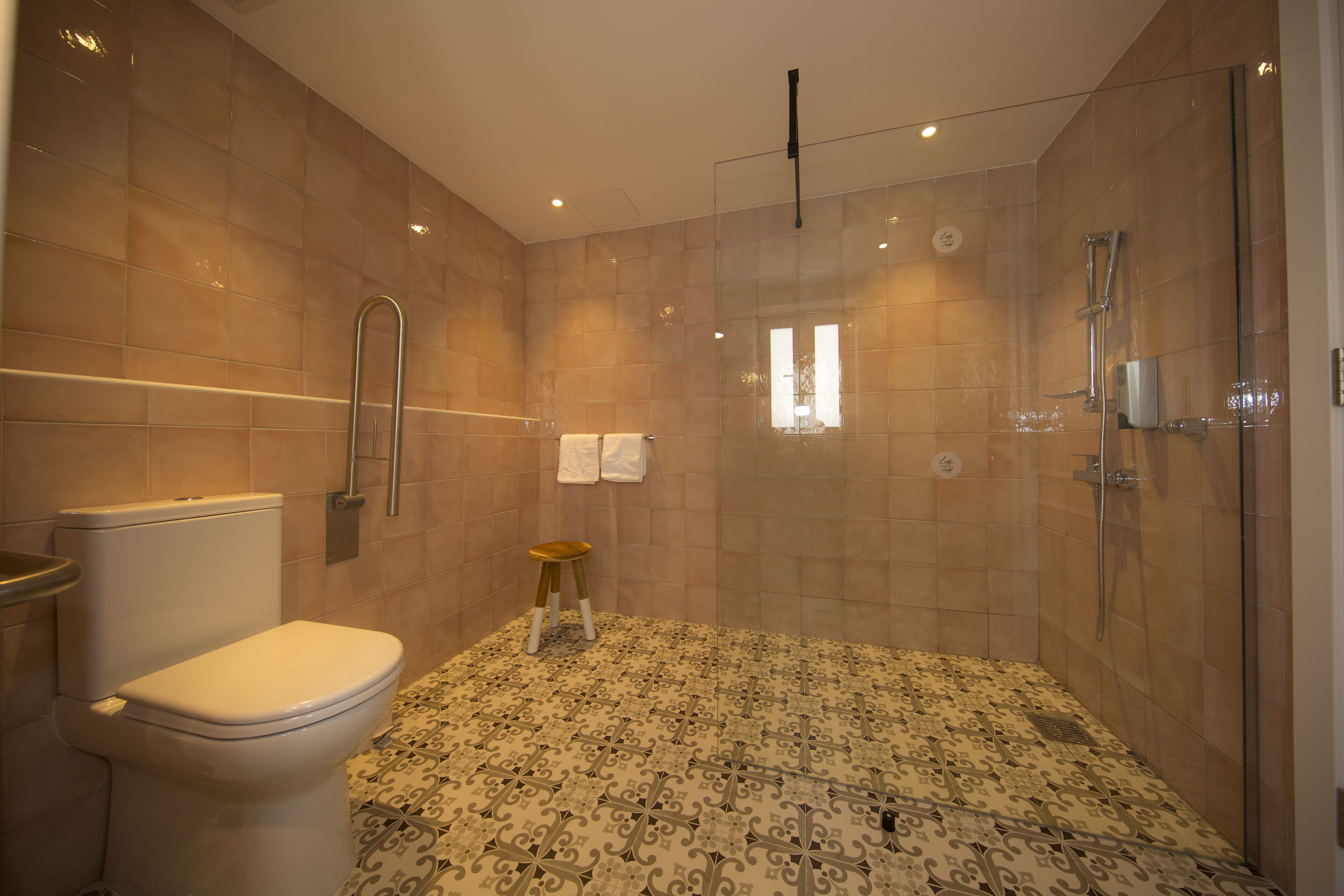 Un baño con inodoro, ducha y piso estampado.