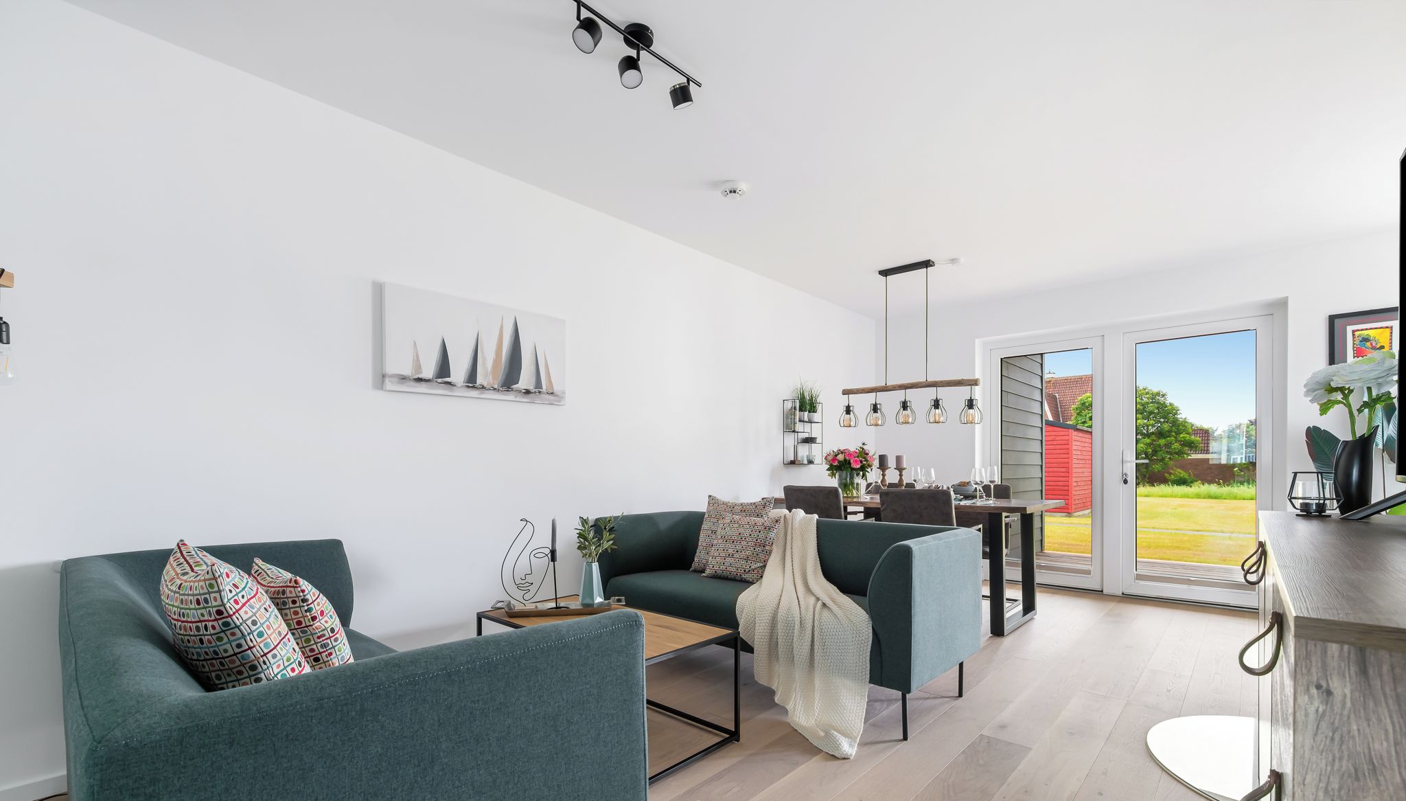 Un salon moderne avec un canapé, une table basse et un coin repas, la cuisine étant visible au fond.