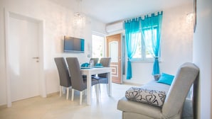 Quarto moderno com uma mesa de jantar, cadeiras, um sofá e uma televisão fixada na parede.