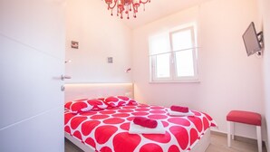 A bedroom with a bed, a window, a chair, and a chandelier. - Apartment with pool, 3 persons, garden, air-conditioned, family-friendly (Nova Vas)