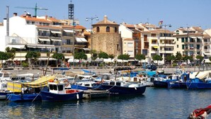 Un puerto deportivo con barcos amarrados, una torre de piedra y edificios con balcones.