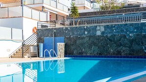 Una piscina con un muro de piedra y una escalera que lleva a un nivel superior.