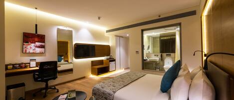 A hotel room with a bed, desk, chair, and a mirror.