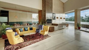 A spacious living area with a sofa set, armchairs, and a coffee table. - The Fern Residency Jamnagar, Series by Marriott (Jamnagar)