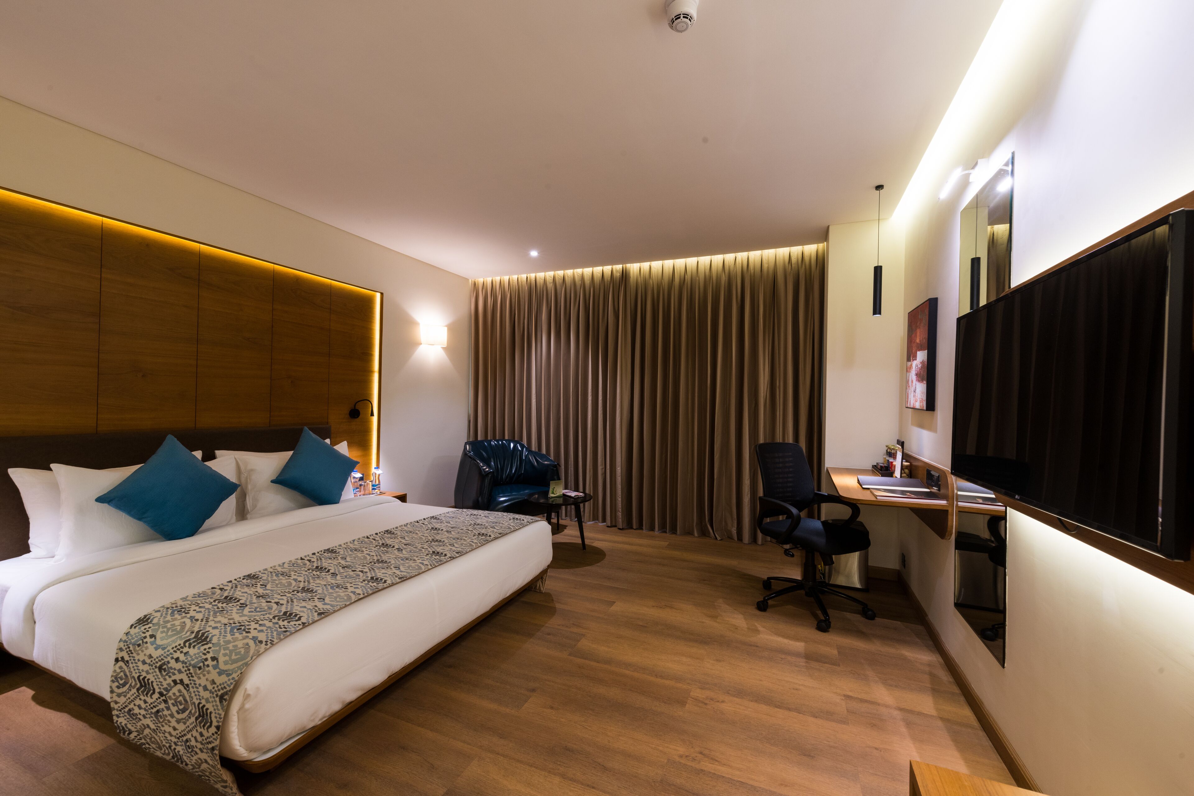 Une chambre d’hôtel avec un grand lit, un bureau, une chaise et un téléviseur.