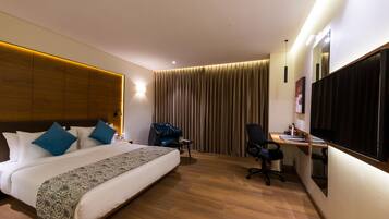 Une chambre d’hôtel avec un grand lit, un bureau, une chaise et un téléviseur.