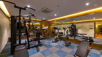 A gym with various exercise equipment, a bench, and a mirrored wall.