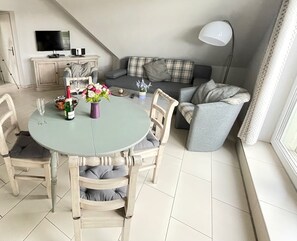 Un comedor con una mesa redonda y sillas, un sofá, un televisor y una lámpara.