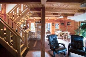 Un intérieur en bois avec un escalier, un coin repas et des fauteuils en cuir.