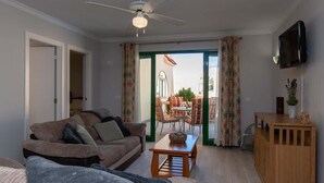 Una sala de estar con un sofá, una mesa de centro y un televisor montado en la pared.