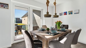 A dining area with a wooden table, grey upholstered chairs, and a hanging rope light fixture.