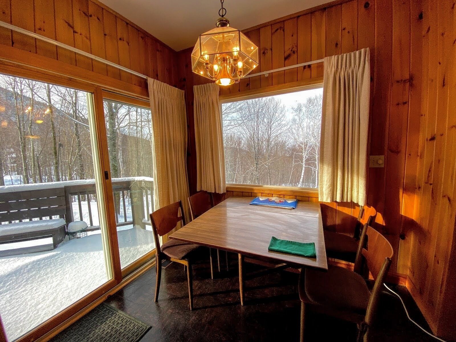 A wooden cabin with a dining table, chairs, and a hanging light fixture.
