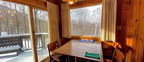 A wooden cabin with a dining table, chairs, and a hanging light fixture.