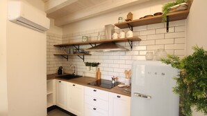 A kitchen with white cabinets, a wooden countertop, a built-in stove, and a white refrigerator.