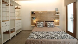 A bedroom with a bed, a wardrobe, a shelf with books, and a window.