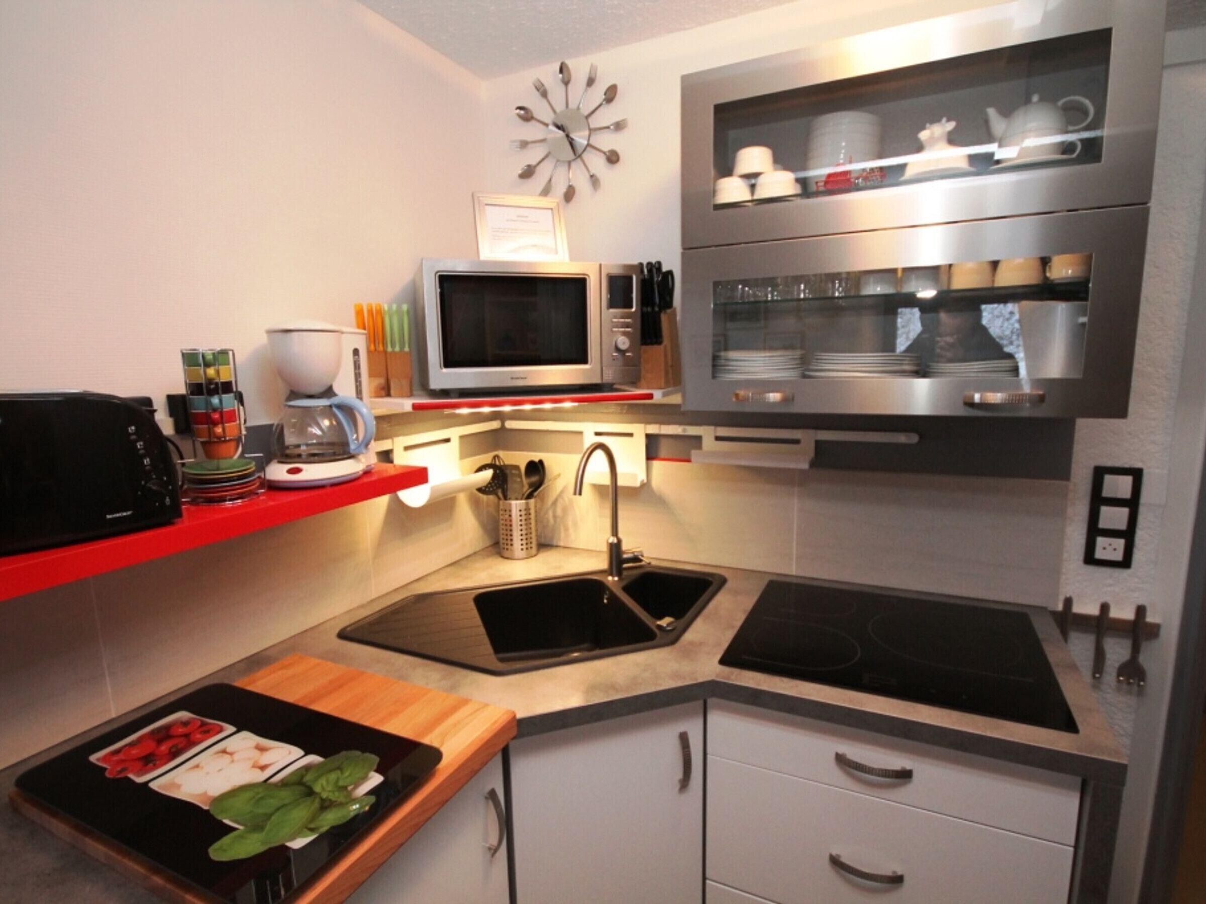 Een kleine keuken met een magnetron, koffiezetapparaat en een spoelbak.