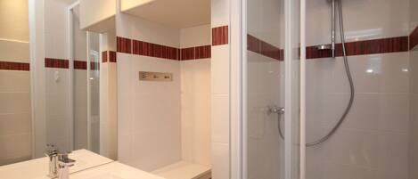 A bathroom with a white sink, mirror, and shower.