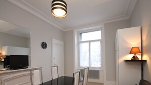 A modern living room with a glass dining table, a sofa, a TV, and a lamp. - Renovated studio in Mont-Dore center with wifi (Mont-Dore)
