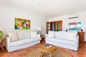 A living room with two white sofas, a wooden coffee table, and a colorful abstract painting. - Villa Casa Nova, Piscina, Wifi, AC gratis (Sant Lluís)